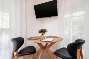 a table with four chairs and a television on a wall at Beechworth House in Beechworth