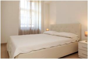 a white bedroom with a large bed with a window at Casa San Carlo nel cuore di Torino in Turin