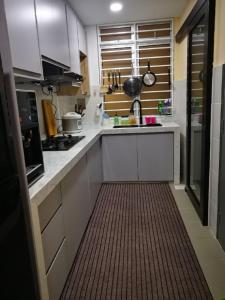 una pequeña cocina con armarios blancos y suelo marrón en Bayu D'Awan Muslim Homestay Putrajaya en Putrajaya