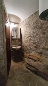 a bathroom with a sink and a stone wall at Linardo low cost in Ano Syros