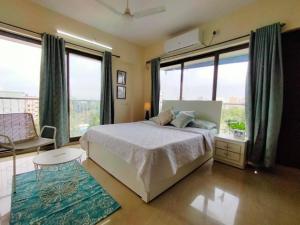 a bedroom with a large bed and large windows at 5 - Studio Velankanni Heights, Behaind Nanavati Hospital, Vile Parle by Connekt Homes in Mumbai