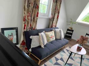 un sofá azul con almohadas en la sala de estar en Lovely Tiny House, en Kelmė