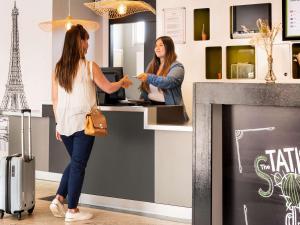 two women standing at a counter in a store at ibis Styles Paris Gare de l'Est Château Landon in Paris