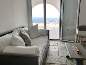 a couch in a living room with a view of the ocean at Sunny Stone Tinos House in Tinos