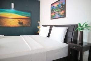 Un dormitorio con una cama blanca y una pintura en la pared en Sunshine Hotel, en Hua Hin