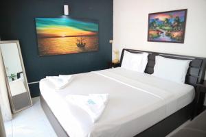 ホアヒンにあるサンシャイン ホテルのベッドルーム1室(壁に絵画が描かれた白い大型ベッド1台付)