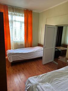 ein Schlafzimmer mit zwei Betten und einem Fenster mit orangefarbenen Vorhängen in der Unterkunft Tsalka in Tsalka + 40 Fotos