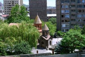 een kleine kerk met twee torens in een stad bij Royal Plaza by Stellar Hotels, Yerevan in Jerevan