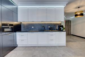 a kitchen with white cabinets and a sink at MALAGA APARTAMENTY BALTICUS in Międzyzdroje