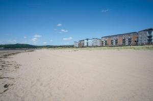 une plage de sable avec des bâtiments en arrière-plan dans l'établissement Swn Y Mor - 4 Bedroom Holiday Home - Llanelli, à Llanelli