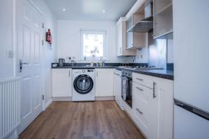 a kitchen with white cabinets and a washing machine at Swn Y Mor - 4 Bedroom Holiday Home - Llanelli in Llanelli