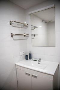 La salle de bains blanche est pourvue d'un lavabo et d'un miroir. dans l'établissement California Apartament Dueñas, à Séville