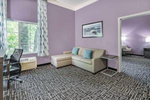 a hotel room with a couch and a mirror at La Quinta Inn & Suites by Wyndham Norfolk in Norfolk