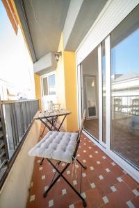 d'un balcon avec une chaise, une table et une grande fenêtre. dans l'établissement California Apartament Dueñas, à Séville