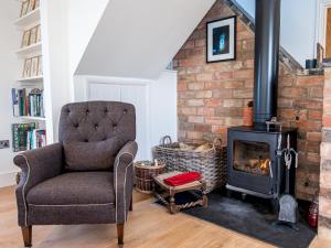 a living room with a chair and a wood stove at Pass the Keys Peaceful Countryside Residence in Pershore