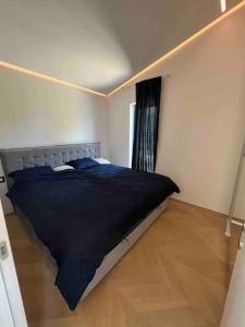 a bedroom with a bed with a black comforter and a window at Sea view 2 bedroom apartment in Portorož