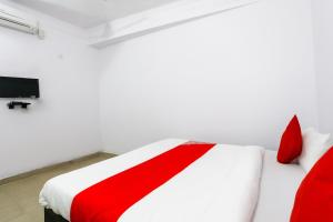 a red and white bed in a room with a tv at OYO Hindon Residency in Ghaziabad