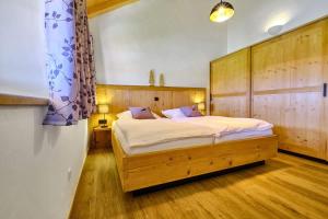 a bedroom with a large bed with a wooden headboard at Huberhof Hinzing Ferienbauernhof in Pittenhart