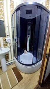 La salle de bains est pourvue d'une douche avec une porte en verre. dans l'établissement UYUT INN Hotel, à Samarcande