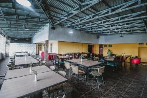 a restaurant with tables and chairs in a room at RedDoorz Plus at Neo Asri Hotel Megamendung Puncak Bogor in Bogor