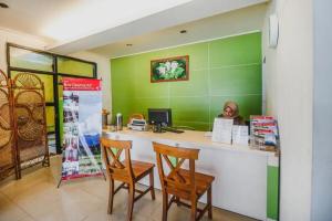 a woman sitting at a desk in a green room at RedDoorz Plus at Neo Asri Hotel Megamendung Puncak Bogor in Bogor