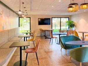 un restaurant avec des tables et des chaises et une télévision dans l'établissement ibis Styles Rennes Cesson, à Cesson-Sévigné