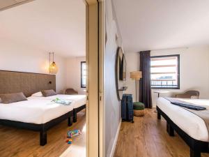una camera d'albergo con due letti e uno specchio di ibis Styles Rennes Cesson a Cesson-Sévigné