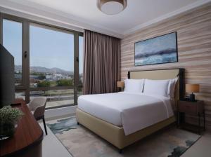 una camera da letto con un letto bianco e una grande finestra di DoubleTree by Hilton Muscat Qurum a Mascate