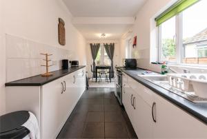 a kitchen with white cabinets and a sink and a window at Lumley House - Delightful 2BR Terraced House near Birmingham in Walsall