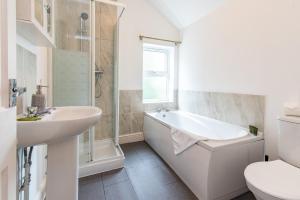 La salle de bains est pourvue d'une baignoire, d'un lavabo et de toilettes. dans l'établissement Lumley House - Delightful 2BR Terraced House near Birmingham, à Walsall