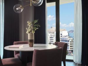 a table with a vase of flowers on it in a room with windows at Grand Hyatt Athens in Athens