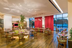 IntercityHotel Muscat في مسقط: غرفة طعام مع طاولات وكراسي ونوافذ