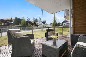 a patio with chairs and a table and a large window at Moderne leilighet - nært flyplass - lader for elbil in Råholt