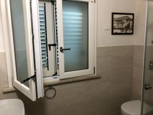 a bathroom with a toilet and a window with shutters at Villa Panoramica in Valderice