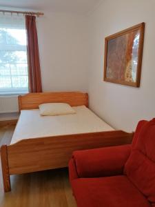 1 dormitorio con 1 cama y 1 sofá rojo en Zielony Zakątek en Krynki