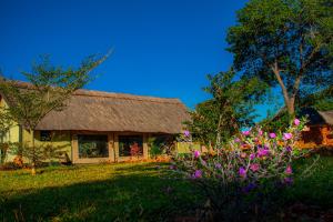 una casa con techo de paja y algunas flores en iroCK Lodge en Victoria Falls