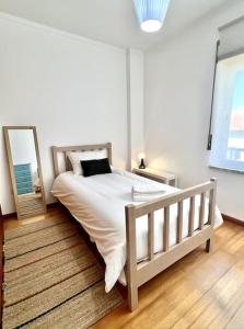 a bedroom with a white bed and a mirror at Porto d’Areia Beach House in Peniche