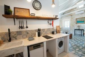 uma cozinha com uma máquina de lavar roupa e um relógio na parede em Malethonas Cottage by All About Paxos em Gaios