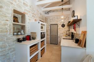 uma cozinha com balcões brancos e uma parede de pedra em Malethonas Cottage by All About Paxos em Gaios