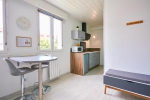 a room with a table and a kitchen with a clock at L'appartement in Pontarlier
