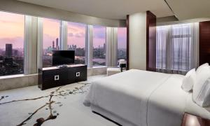 a bedroom with a bed and a tv and large windows at The Westin Pazhou in Guangzhou