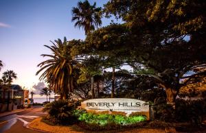 a sign for a resort with palm trees and a street at Beverly Hills in Durban