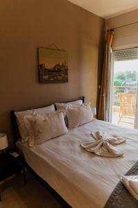 a bedroom with a bed with white sheets and a window at Villa de N.A.P.E in Hanioti
