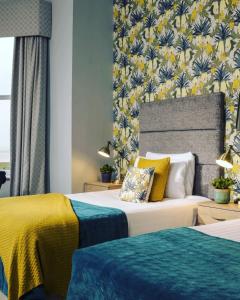 sypialnia z 2 łóżkami w kolorze żółtym i niebieskim w obiekcie Clifton Arms Hotel w mieście Lytham St Annes