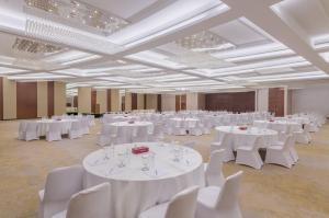 IntercityHotel Muscat في مسقط: غرفة كبيرة مع طاولات بيضاء وكراسي بيضاء