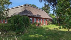 a red house with a thatched roof in a yard at Under Valnødden in Stubbekøbing