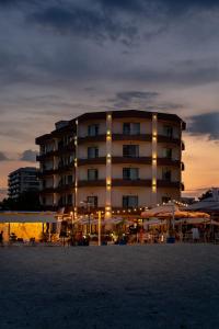 a large building with tables and umbrellas in front of it at Hotel Bueno in Mamaia