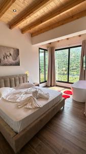 ein Schlafzimmer mit einem großen Bett und großen Fenstern in der Unterkunft Hotel Nemercka in Përmet