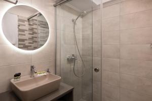 a bathroom with a sink and a shower with a mirror at Lampraki Luxury Apartments in Rhodes Town