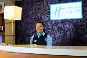 uma mulher à frente de uma secretária com um cartaz em Holiday Inn Express - Glasgow - City Ctr Riverside, an IHG Hotel em Glasgow
